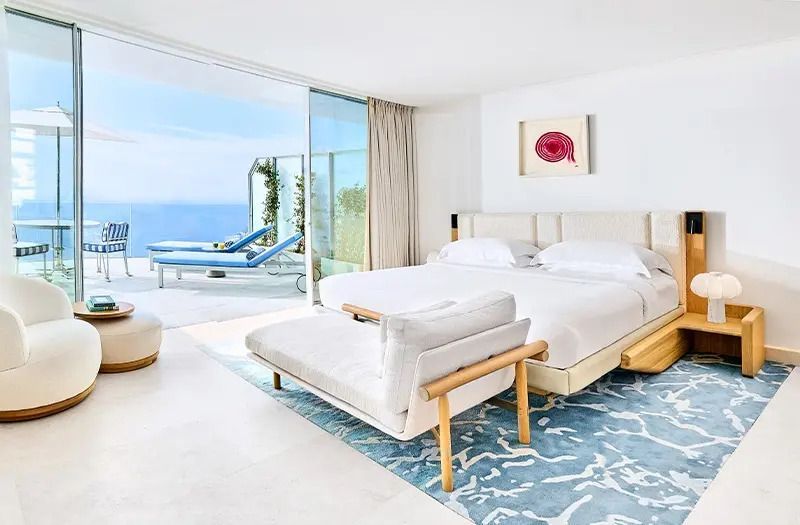 Modernes Hotelzimmer mit Meerblick, Doppelbett und Balkon.