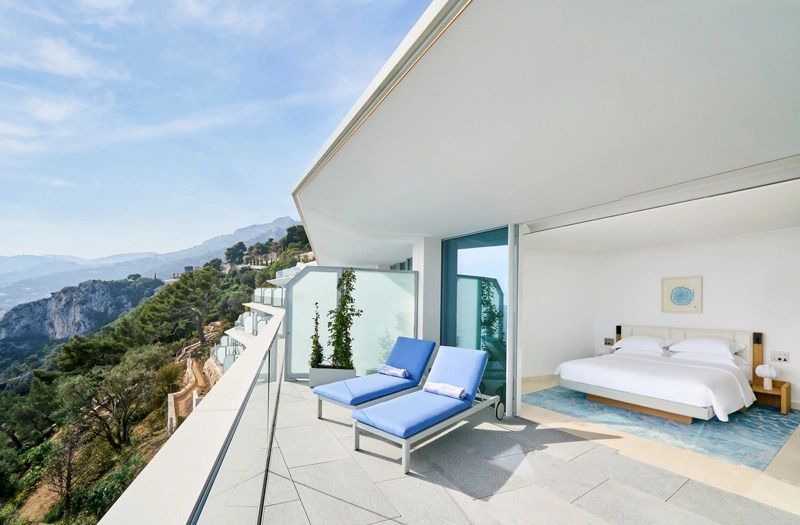 Privater Balkon mit zwei blauen Sonnenliegen und Blick aufs Meer.