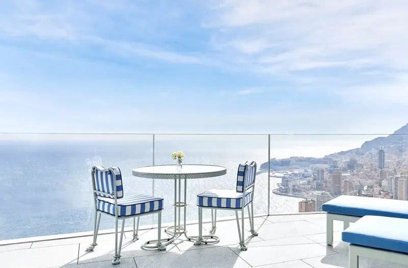 Terrasse mit Tisch und Stühlen, Panoramablick auf Küste und Meer.