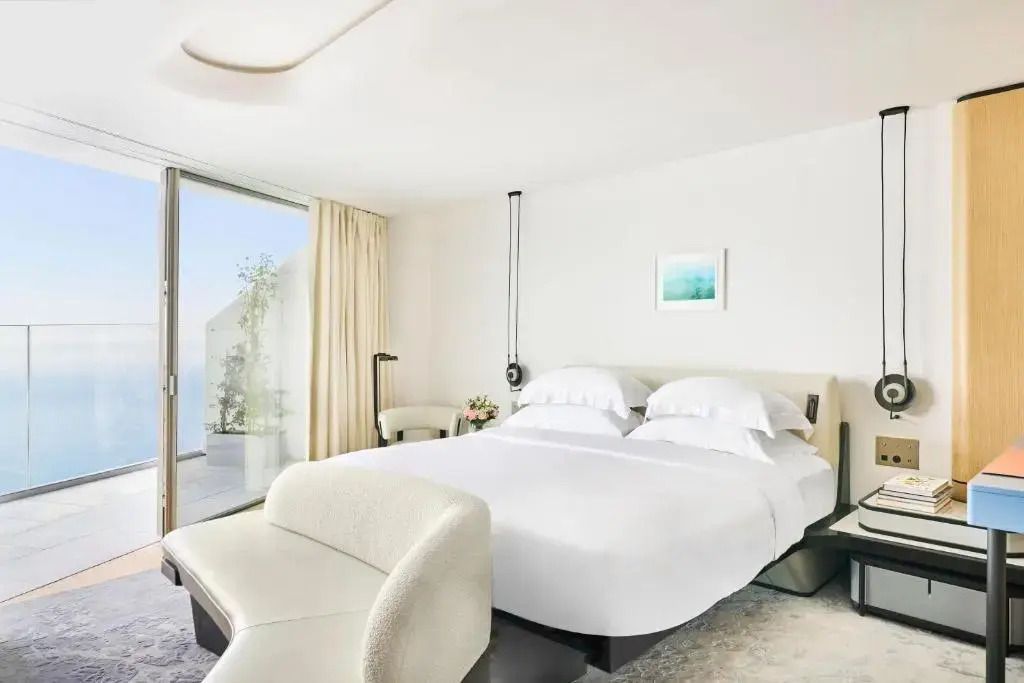 Helles Hotelzimmer mit modernem Doppelbett und Zugang zur Terrasse