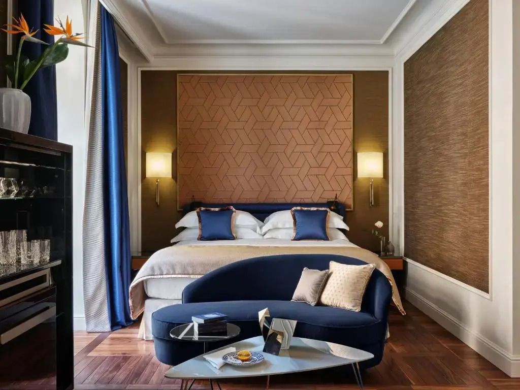 Elegantes Zimmer mit Doppelbett, goldener Wandverkleidung und blauen Akzenten.