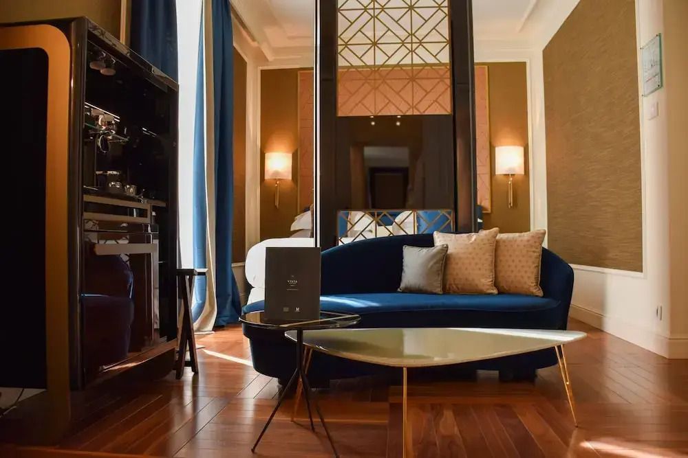 Moderne Suite mit Sofa, goldenen Details und großem Fenster.