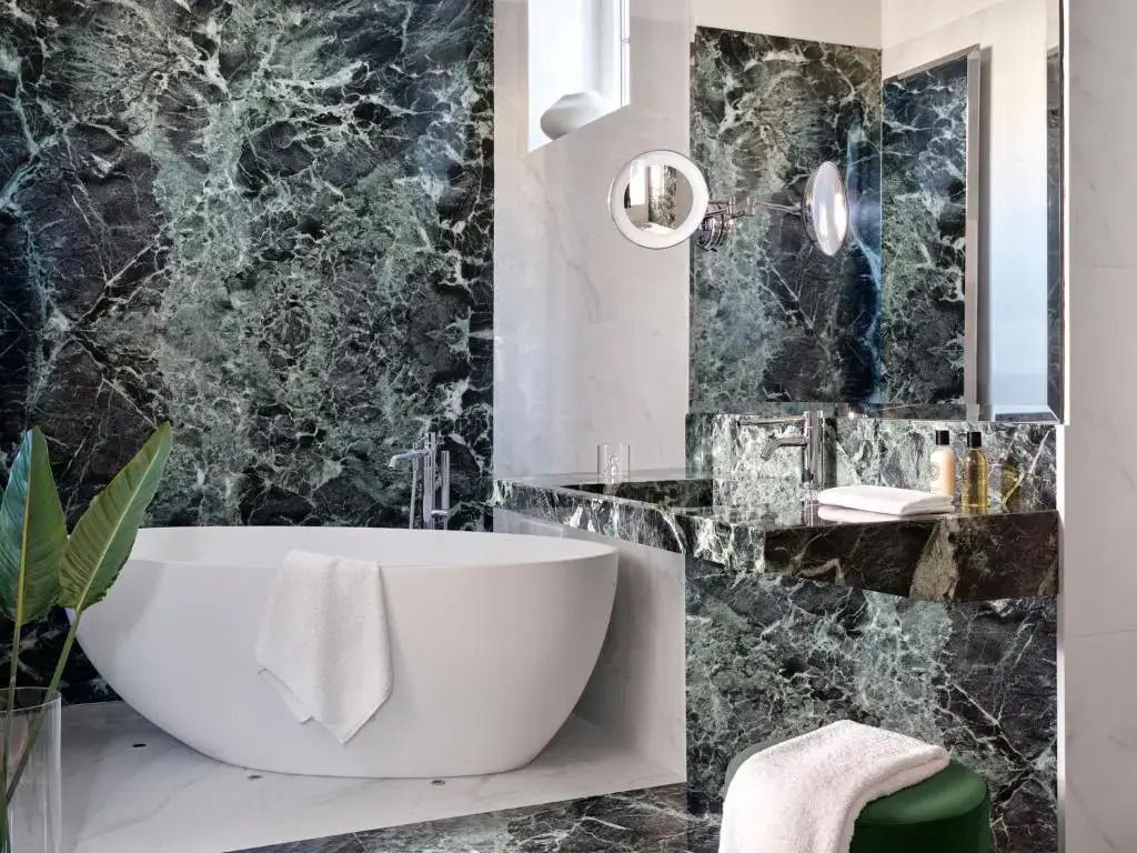 Luxuriöses Badezimmer mit Marmorwänden und frei stehender Badewanne