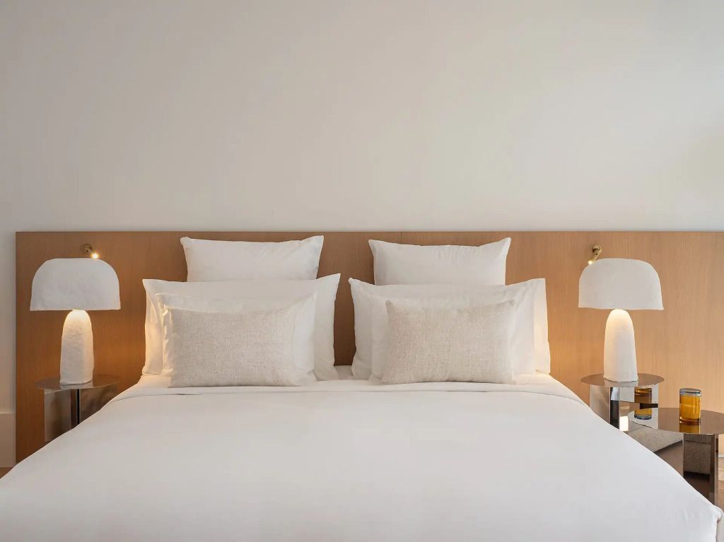 Elegantes Schlafzimmer mit Doppelbett und minimalistischer Beleuchtung.