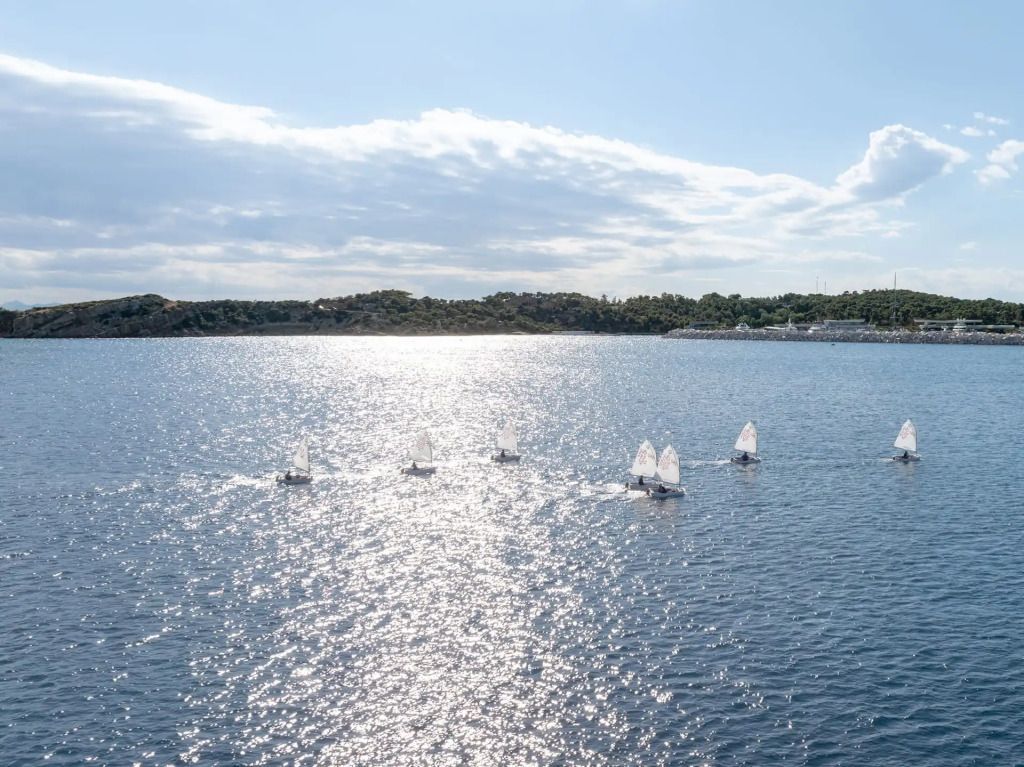 Blick auf die glitzernde Marina mit kleinen Segelbooten auf dem Wasser.