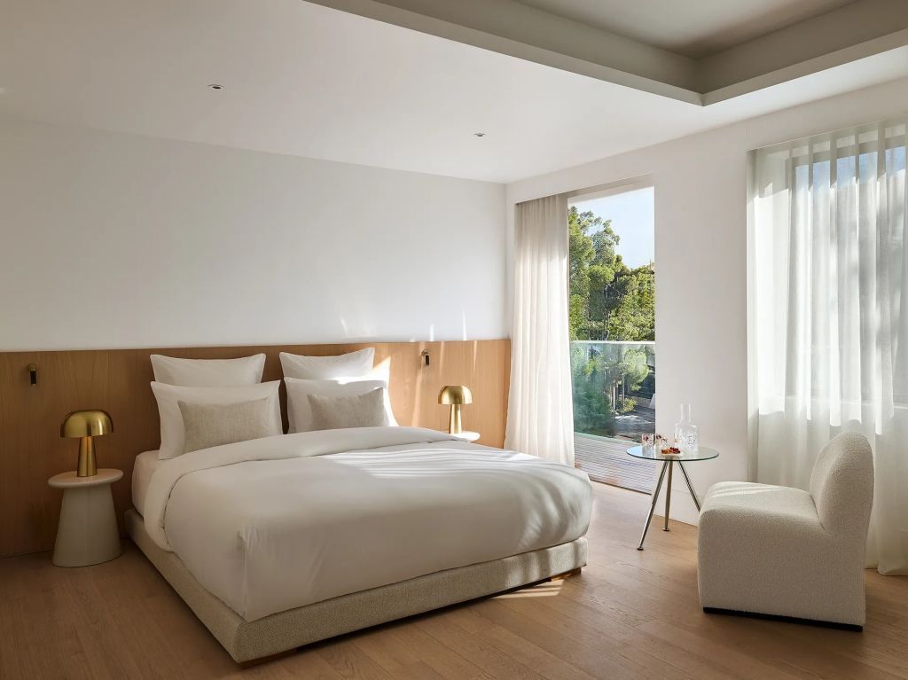 Geräumiges Zimmer mit Doppelbett und Blick auf die Terrasse durch ein großes Fenster