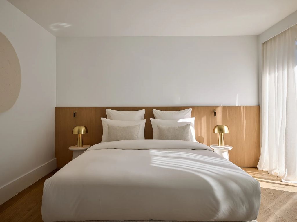 Helles Doppelzimmer mit elegantem Bett und zwei goldenen Nachttischlampen