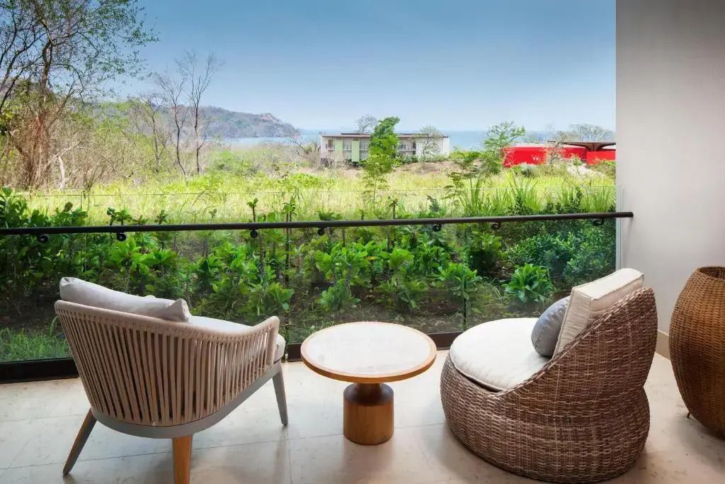 Balkon mit eleganten Sitzmöbeln und Blick auf grüne Landschaft und Meer
