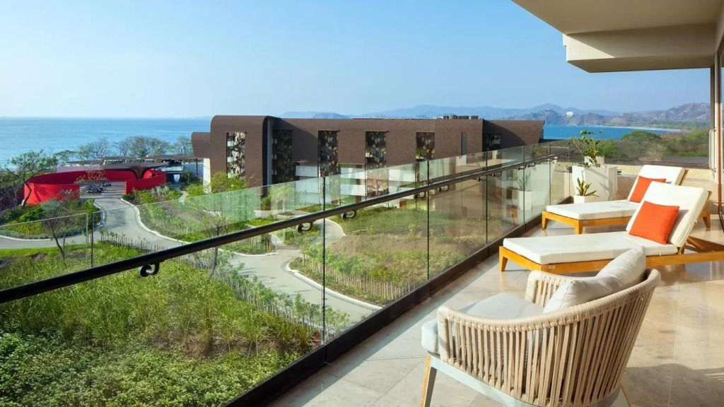 Balkon mit Blick auf grüne Anlage und Meer im Hintergrund