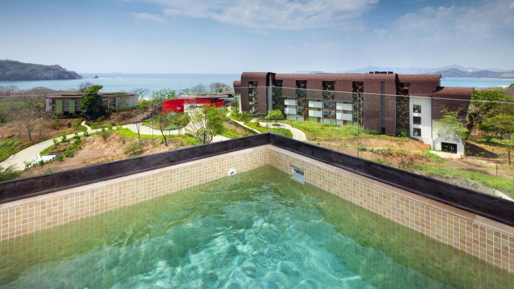 Pool mit Blick auf Hotelgebäude und Meer im Hintergrund