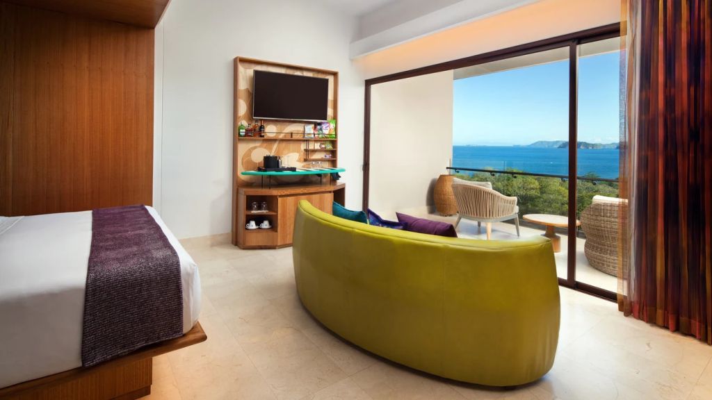 Modernes Zimmer mit Doppelbett, Fernseher und Balkon mit Meerblick