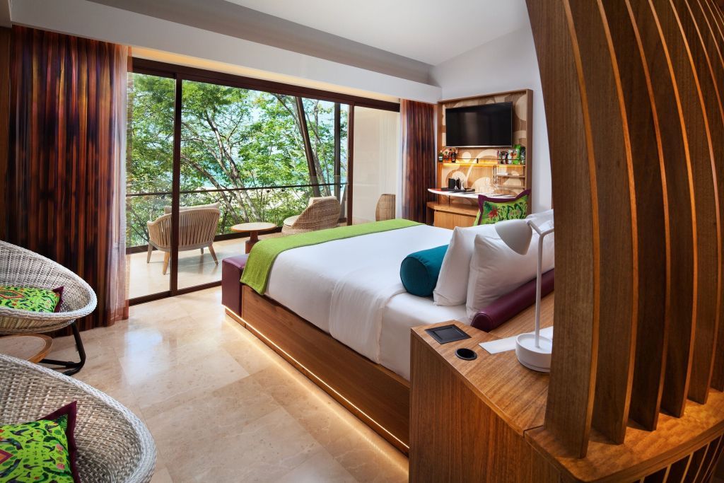 Moderne Suite mit Blick auf einen dichten Wald, Doppelbett mit farbiger Bettwäsche