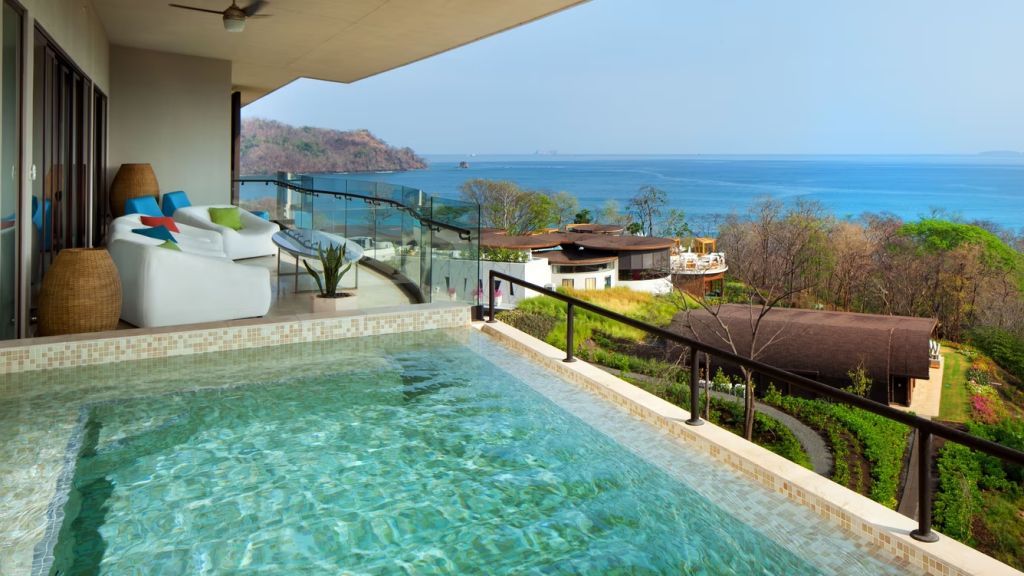 Infinity-Pool auf dem Balkon mit Meerblick und üppiger Vegetation.