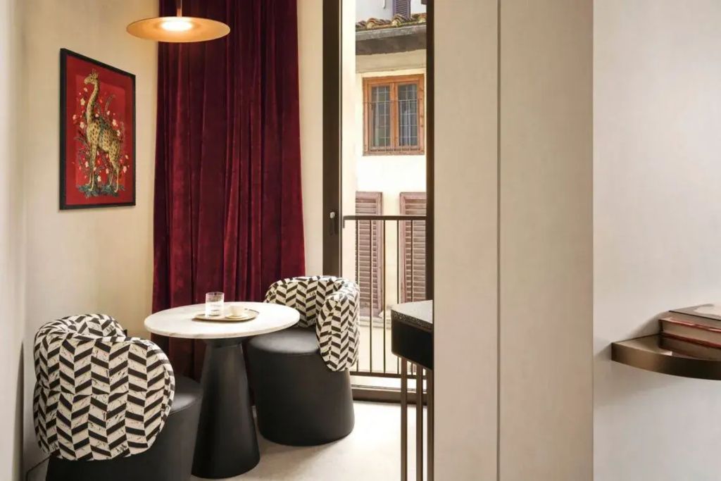 Gemütlicher Sitzbereich mit kleinem Tisch und zwei Sesseln vor rotem Vorhang und Balkon