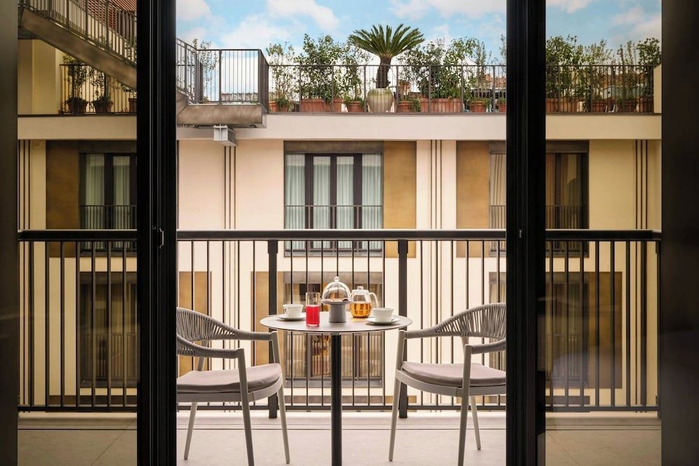 Balkon mit zwei Stühlen und Tisch. Blick auf urbanen Innenhof