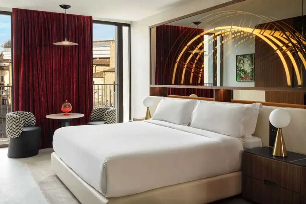 Premier Doppel Suite mit großem Bett, stilvoller Beleuchtung und Balkon.