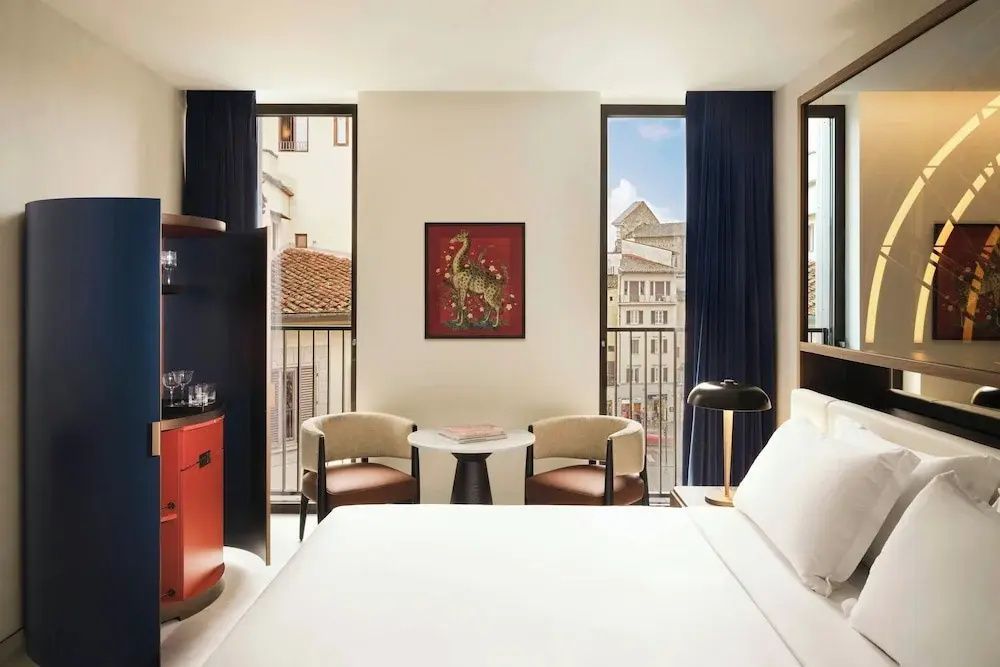 Helles Hotelzimmer mit Balkon und zwei Sesseln vor Kunstwerk