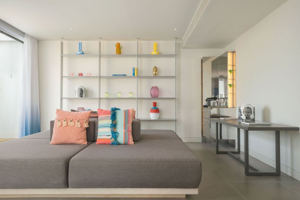 Moderne Lounge mit grauem Sofa und dekorativen Kissen vor Regalwand