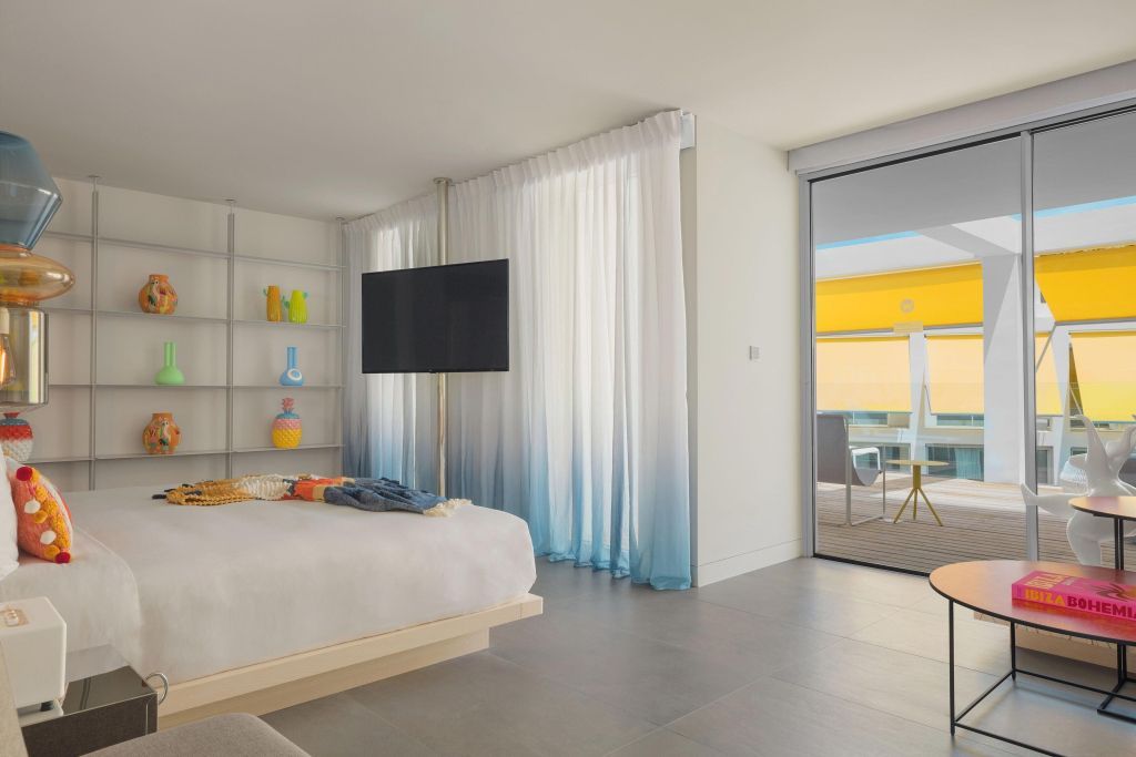 Zimmeransicht mit großem Bett, Flachbildschirm und Zugang zur Terrasse.