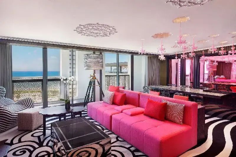 Helles Wohnzimmer mit rosa Sofa, großen Fenstern und Meerblick.