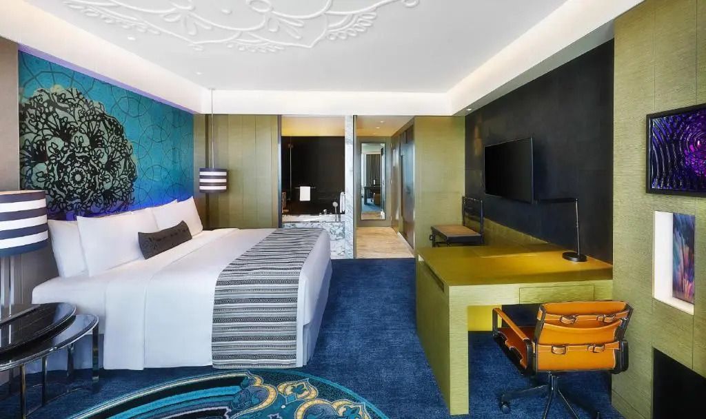 Modernes Hotelzimmer mit Doppelbett, Schreibtisch und Wandkunst im W Muscat.