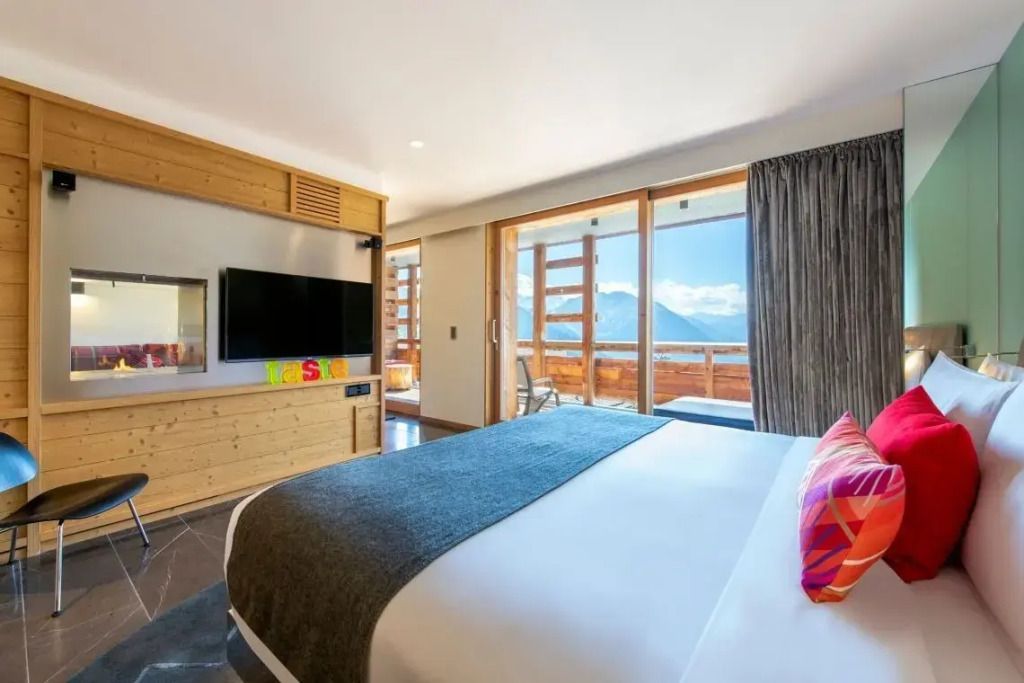 Gemütliches Zimmer mit Blick auf die Alpen und einem großen Flachbildfernseher.