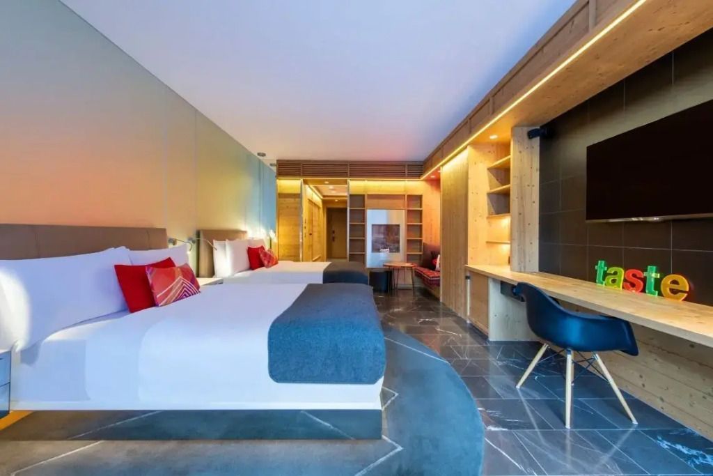 Geräumiges Hotelzimmer mit zwei Einzelbetten, Schreibtisch und stylishem Dekor.