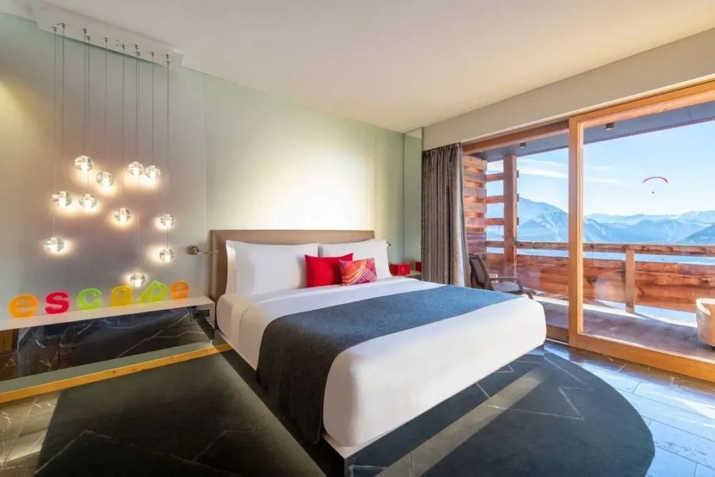 Modernes Hotelzimmer mit Doppelbett und Balkonblick auf die Alpen