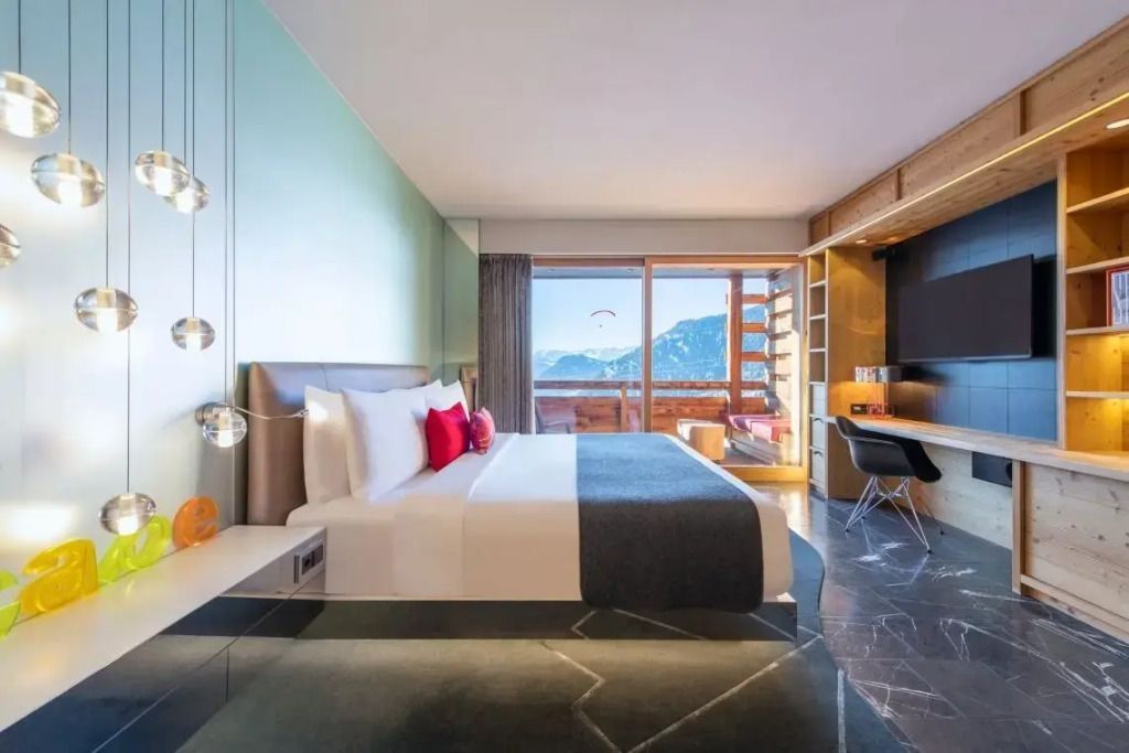 Hotelzimmer mit großem Bett und Blick auf Berge durch Balkon