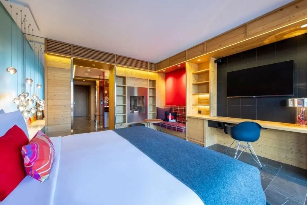 Zimmer mit Schreibtisch, TV und roten Akzenten im Hotel W Verbier