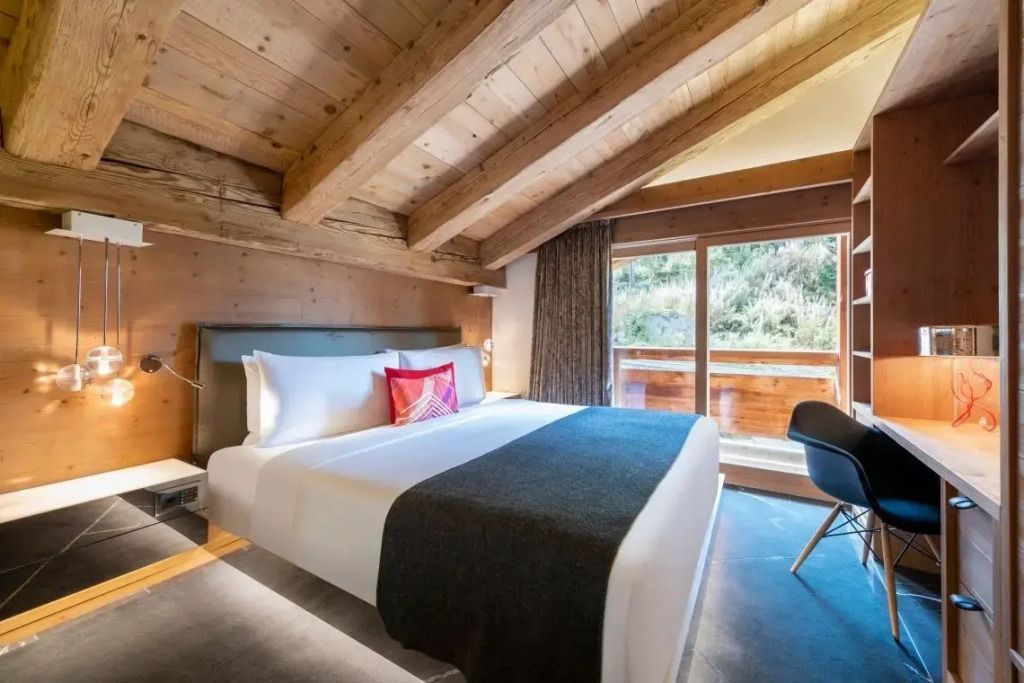 Gemütliches Schlafzimmer mit Holzbalkendecke und großem Fenster
