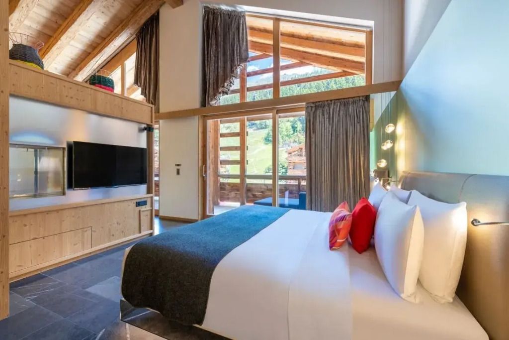 Helles Schlafzimmer mit Doppelbett und Panoramafenster in Chalet-Stil