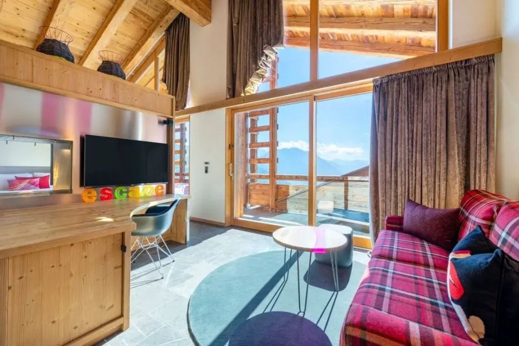 Wohnbereich mit Sofa, Couchtisch und Ausblick auf die Berge