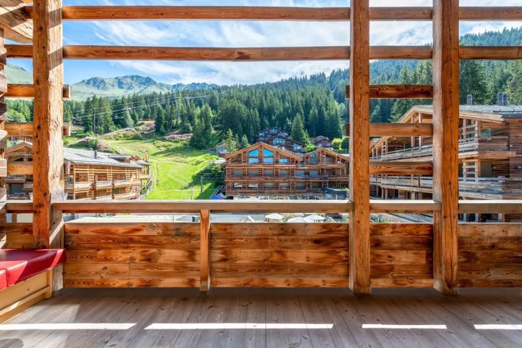 Balkon mit Holzgeländer und Blick auf umgebende Berge und Chalets