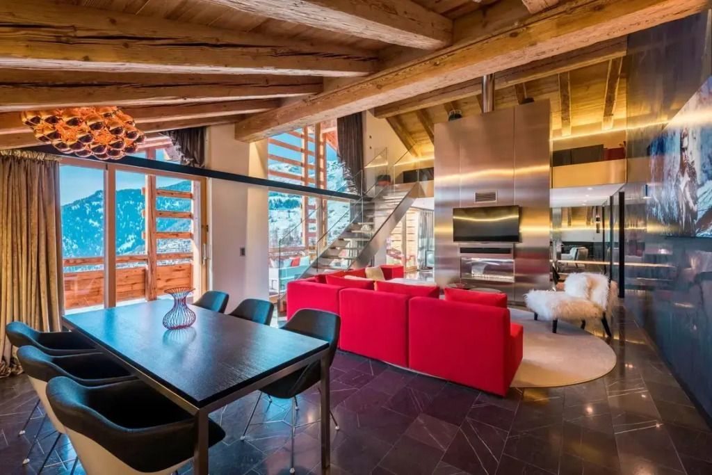 Ess- und Wohnbereich der WOW Suite mit Holzbalkendecke und Panoramafenstern.