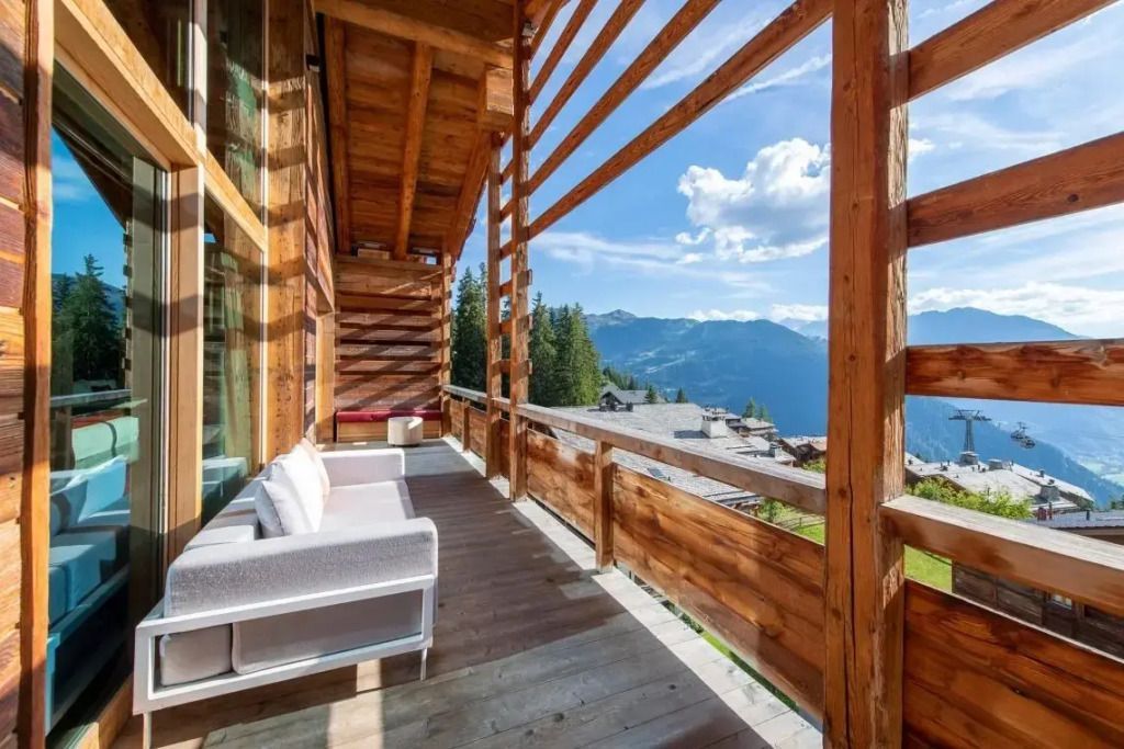 Holzveranda der WOW Suite mit gemütlichen Sofas und Bergblick unter blauem Himmel.