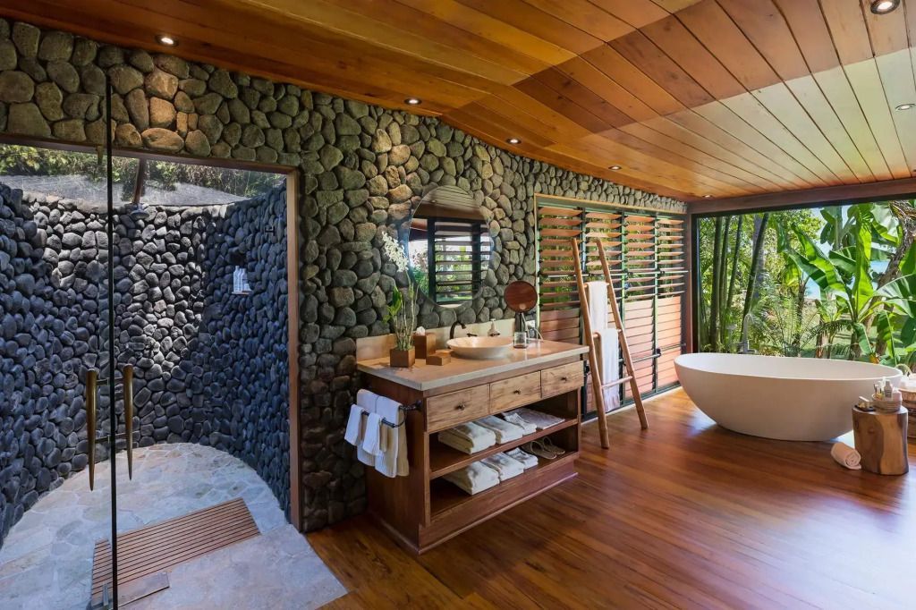 Elegantes Badezimmer mit Natursteinwänden und freistehender Badewanne