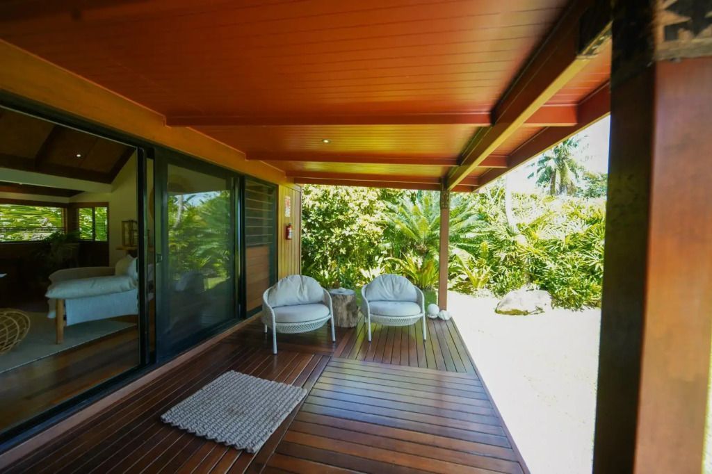 Überdachte Veranda mit zwei Stühlen und Blick auf tropischen Garten