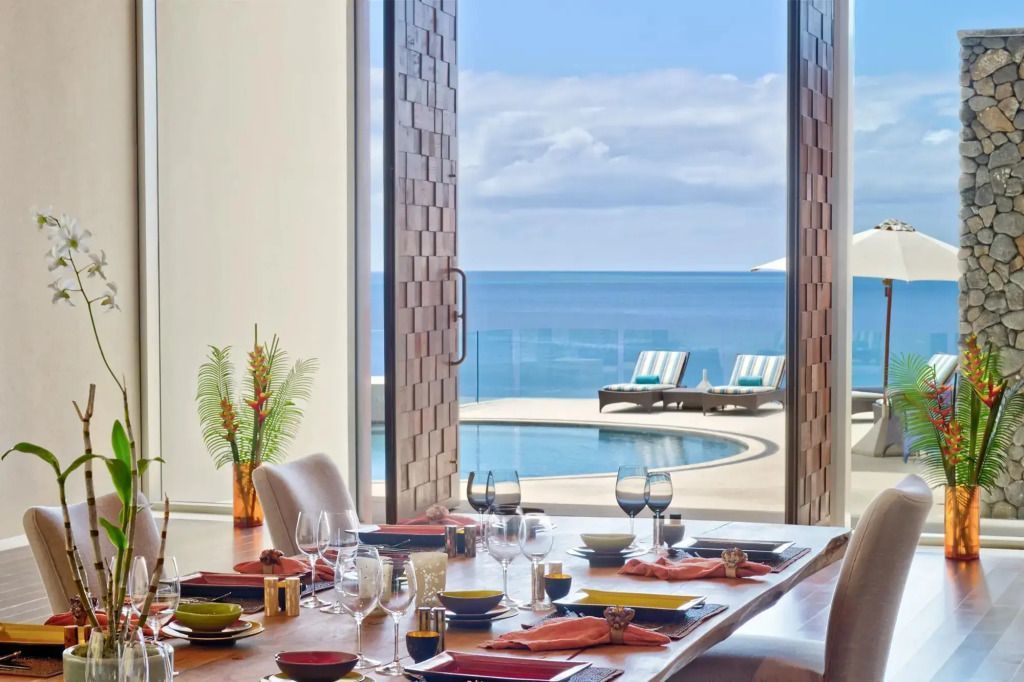Eingedeckter Tisch mit Blick aufs Meer und einen Infinity-Pool im Hintergrund