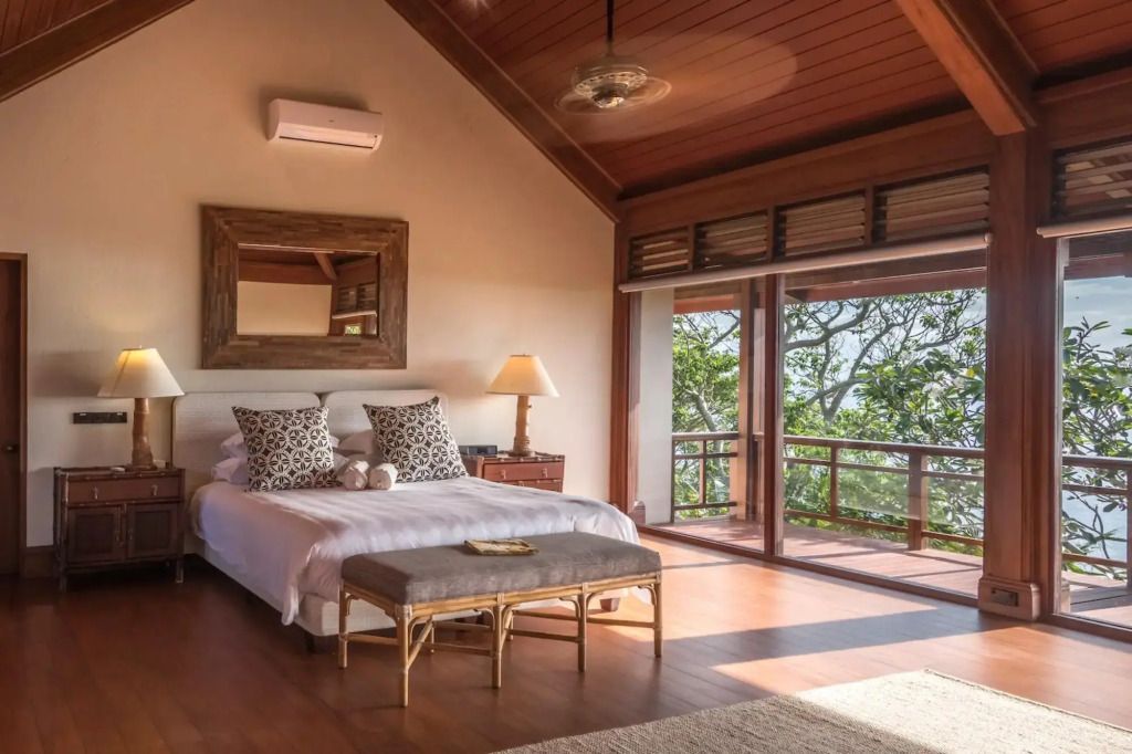 Helles Schlafzimmer mit Holzdecke und großem Fenster mit Blick ins Grüne