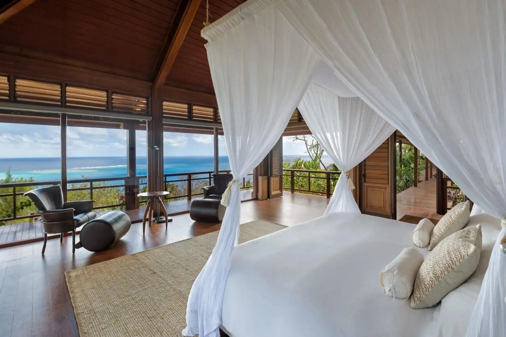 Luxuriöses Schlafzimmer mit Himmelbett und Panoramafenster mit Meerblick