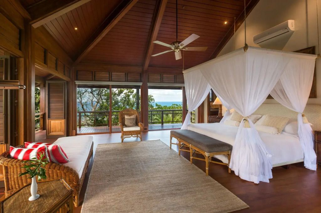 Großzügiges Schlafzimmer mit Himmelbett und Ausblick auf tropische Landschaft