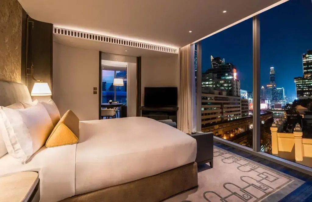 Eck-Suite mit Doppelbett und nächtlichem Stadtblick durch große Fenster