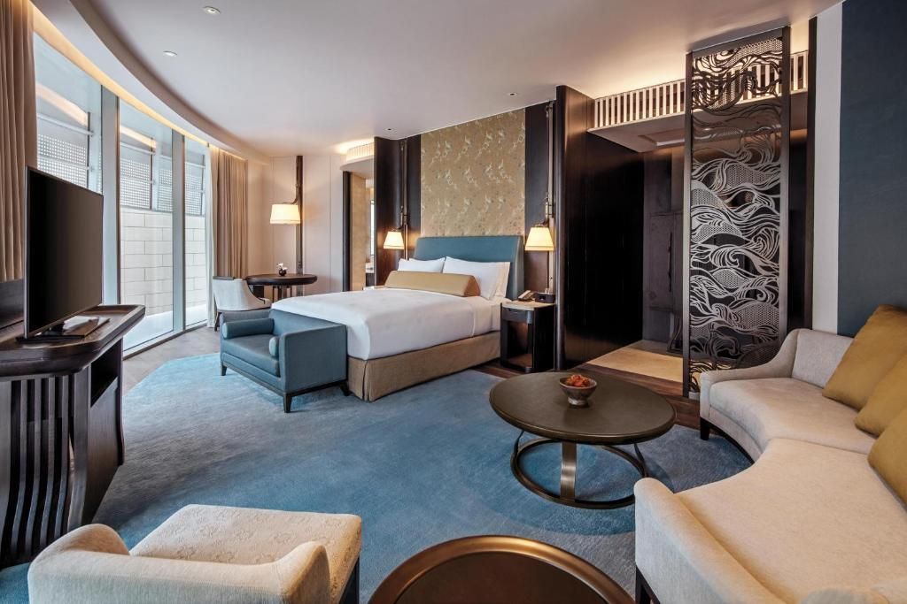 Großzügiger Wohnbereich in der Deluxe Suite mit modernen Möbeln und großen Fenstern