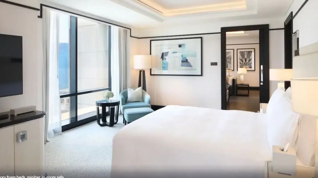Geräumiges Zimmer mit großen Fenstern und luxuriösem Doppelbett.