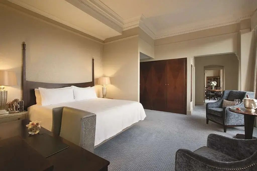 Großes Bett in lichtdurchflutetem Zimmer mit eleganten Holzmöbeln