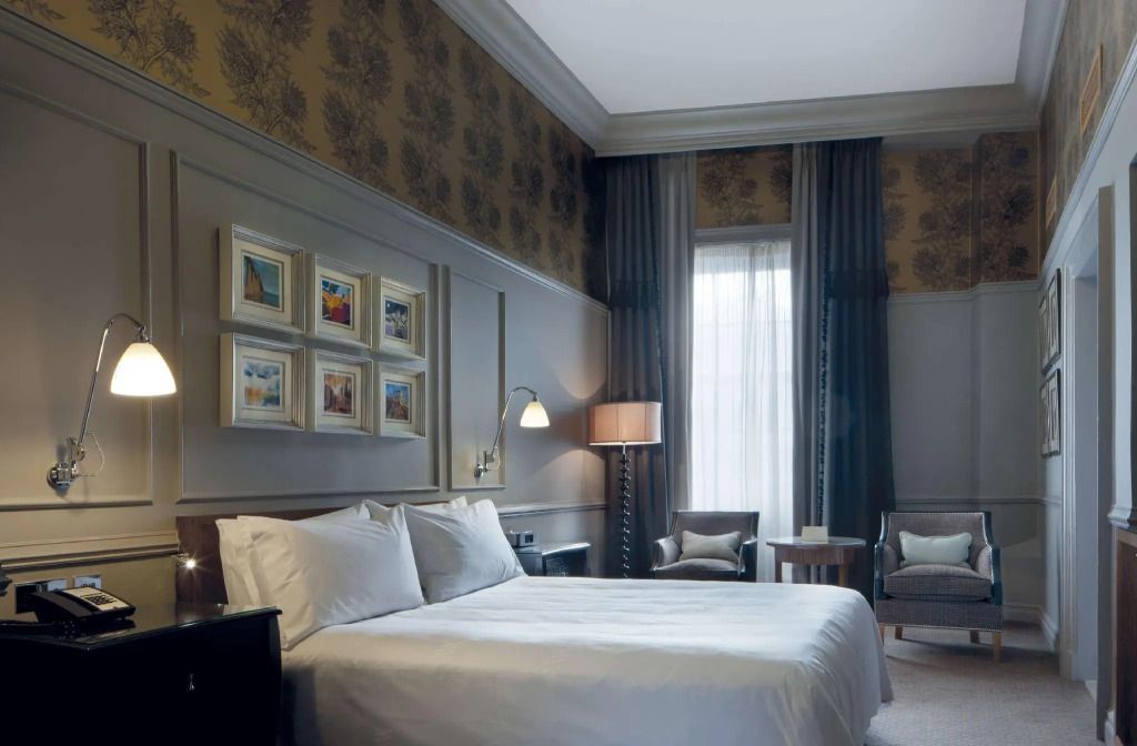 Gemütliches Deluxe Doppelzimmer mit Kunstwerken und eleganten Vorhängen.