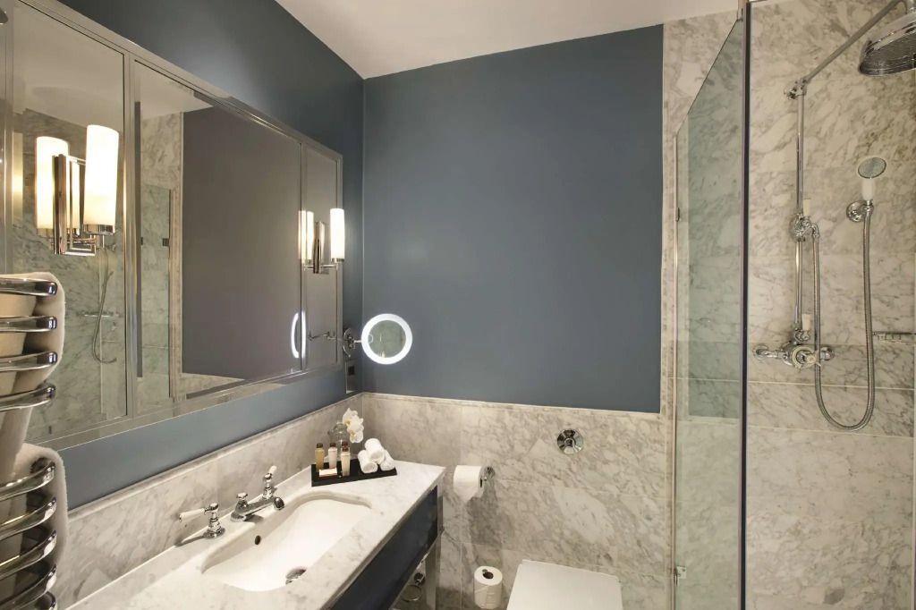 Elegantes Badezimmer mit Marmorverkleidung und Kosmetikspiegel.