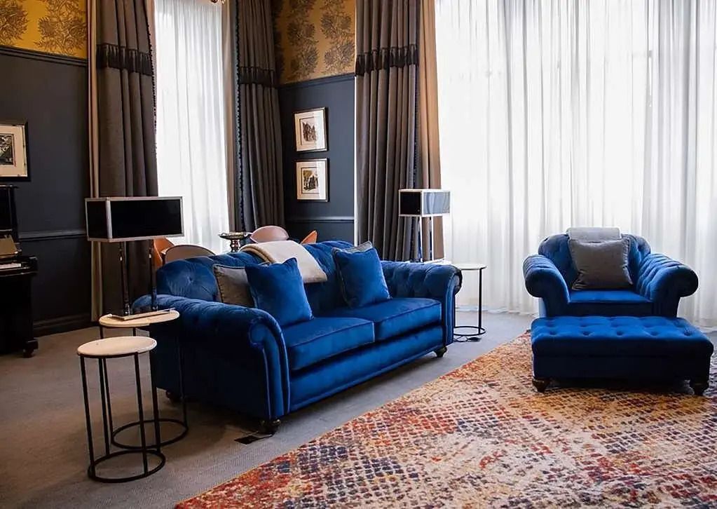 Luxuriöser Wohnbereich mit blauen Samtsofas und großzügigen Fenstern
