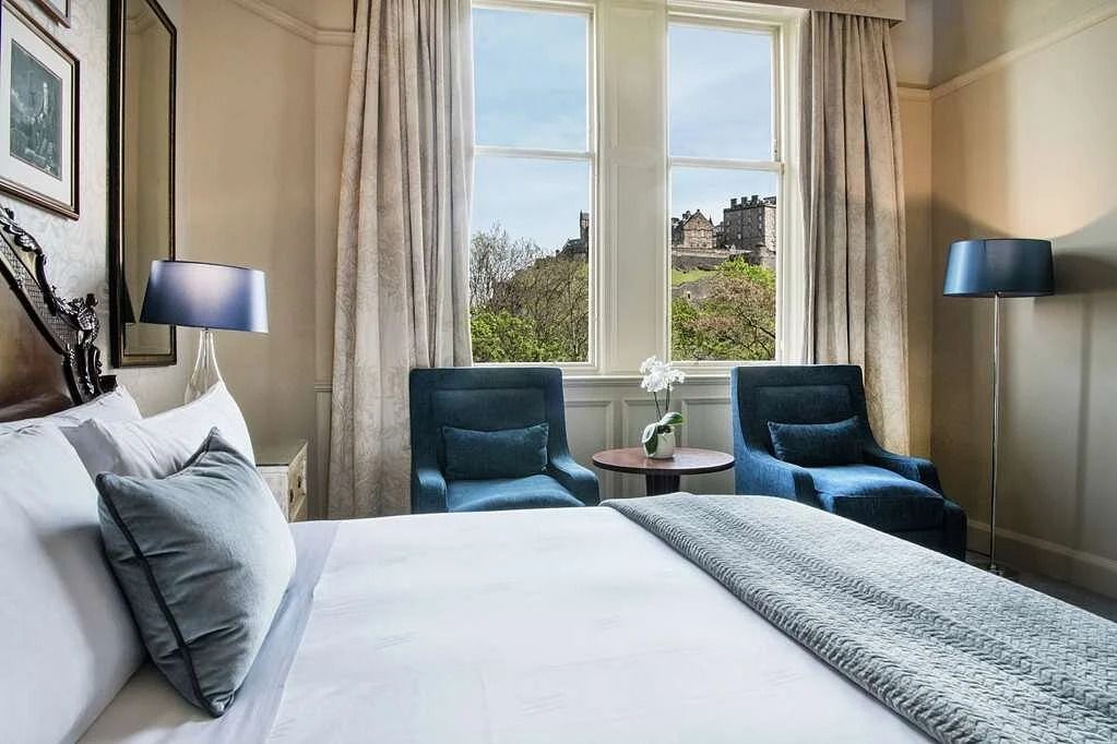 Helles Schlafzimmer mit Doppelbett und Blick auf Edinburgh Castle durch große Fenster